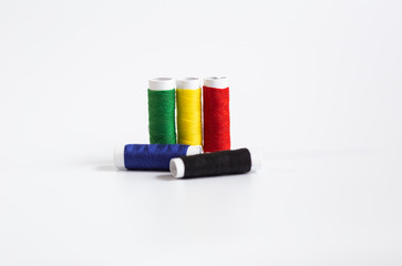 Threads of different colors with the coils in a row and swing needle on white background
