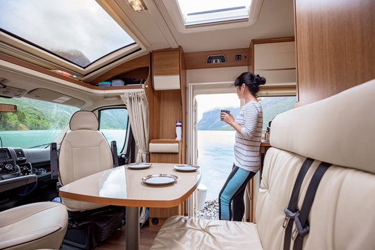 Woman In The Interior Of A Camper RV Motorhome With A Cup Of Coffee Looking At Nature.