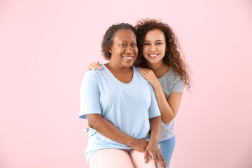 Portrait of African-American woman with her daughter on color background
