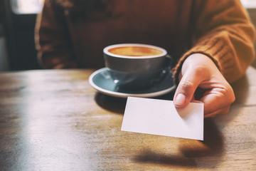 A woman holding and giving a blank empty business card to someone
