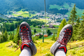 View from the chairlift to the mountain valley. In the foreground, trekking shoes.