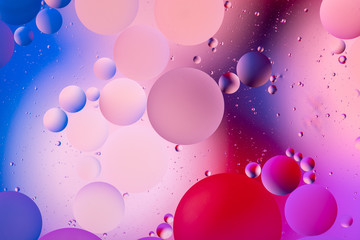 bright oily drops in water with colorful background, close-up 