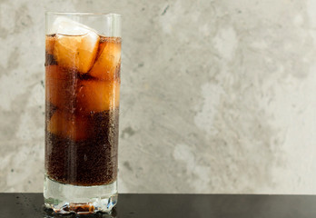 Glass of cola with ice on a gray background. The concept of non-alcoholic soft drinks. Copy space