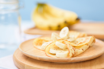 Banana pancakes on a wooden plate for breakfast in the summer