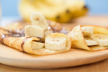 Banana pancakes on a wooden plate for breakfast in the summer