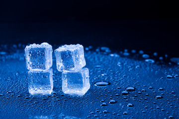 Wet ice cubes and water drop on blue background.