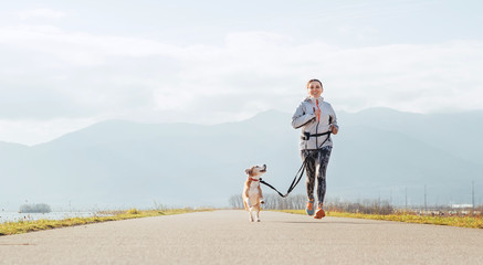 Bright sunny Morning Canicross exercises. Female runs with his beagle dog and happy smiling.