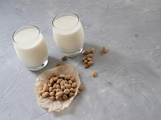 Pistachio milk in a glass Cup and pistachio nuts on a gray concrete background. Copy space.