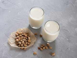 Pistachio milk in a glass Cup and pistachio nuts on a gray concrete background. Copy space.