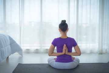 A beautiful young woman sitting in a yoga room in a calm and relaxed manner. Light, comfortable, light window background comes in the morning. Health care concepts