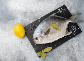 Fresh raw fish pompano and spice ingredients on table