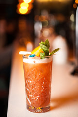 Close-up orange cocktail with orange and mint on the bar, blurred background.