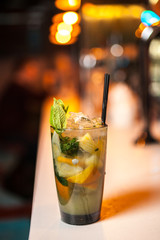 Close-up mojito cocktail with lime and mint on the bar, blurred background.