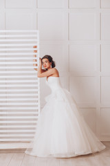 Young beautiful bride in a luxurious wedding dress in the studio on white background