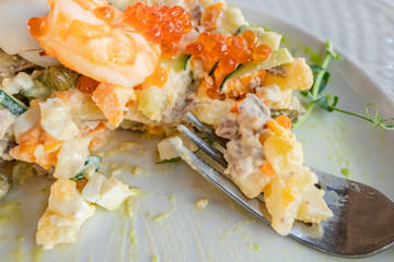 Olivier salad cooked according to the first recipe is half eaten.