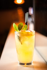 Orange cocktail with orange and mint on the bar, blurred background.
