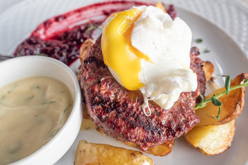 chopped beef cutlet, poached egg, potatoes and sauce.
