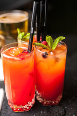 Three orange cocktails on dark bar