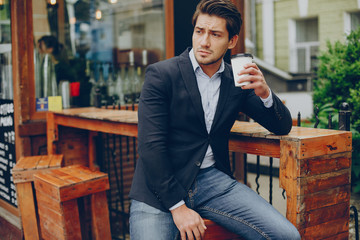 Man in a stylish suit. Businessman in a summer city. Male drinking a coffee