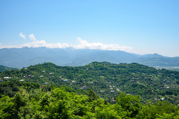 view of a mountain village located on a mountainside on a bright sunny day, with clouds in the sky.