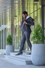 handsome african american businessman walking on stairs of office building