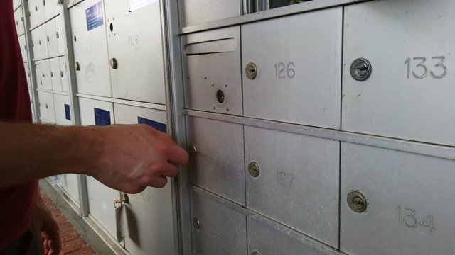 White male hands opening a lockbox door at a bank out post office.