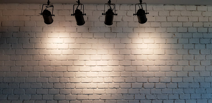 Hanging spotlight illuminate at white brick wall background with copy space