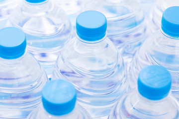 Rows of plastic bottles, selective focus. Necks of plastic bottles of still water with blue caps, close up