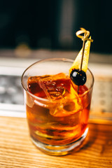 Close up cocktail with with olive and orange peel on the bar, blurred background.