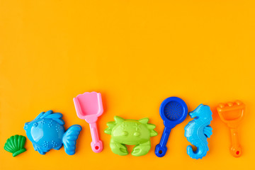 Colorful play sand toys set on the yellow background with space.Concept for summer activity, traveling, holidays or sales promotion.