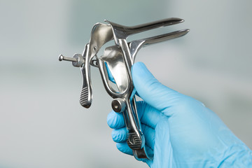 doctor's hand in medical gloves presents a medical speculum