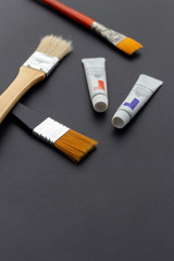 brushes and paint tubes closeup on black table with soft-focus and over light in the background