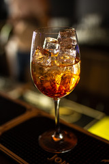 Close-up orange cocktail on the bar, dark blurred background.