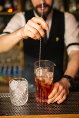 Close-up of expert bartender making cocktail on the bar, blurred background.