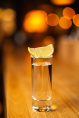Close-up shot tequila with lime on the bar, blurred background.