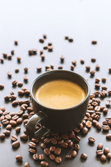 hot espresso and coffee bean on black table with soft-focus and over light in the background. top view