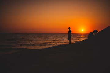 Silhouettes of a Man in front of a breathtaking sunset at the seaside