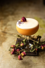 Close up orange cocktail with dried rose decor on the bar
