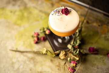 Close up orange cocktail with dried rose decor on the bar