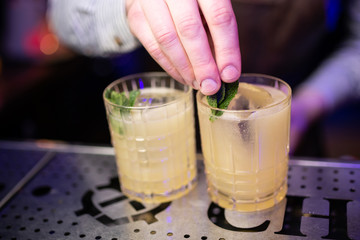 Close-up of expert bartender making cocktail on the bar, blurred background.