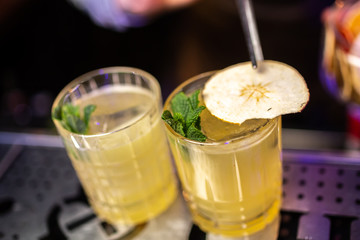 Close-up cocktail with mint and dried pear on the bar, blurred background.