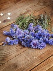 Flowers of cornflowers lie on a wooden table. View from above. A bouquet of blue flowers on a wooden background.