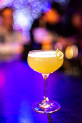Close-up cocktail with lemon peel on the bar, blurred background.