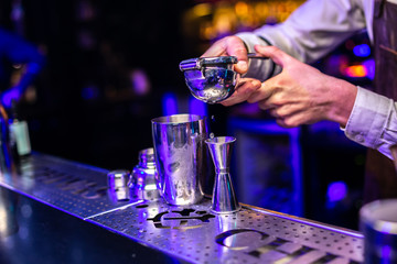 Close-up of expert bartender making cocktail on the bar, blurred background.