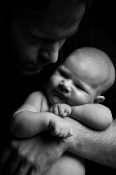 black and white portrait of a newborn baby in the arms of a dad