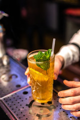 Close-up of expert bartender serves cocktail on the bar, blurred background.