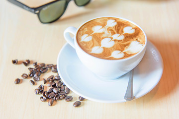 hot coffee and coffee bean on table / hot cappuccino with nice pattern milk foam 