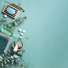 Soap, eucalyptus, towels, massage brush, salt, aroma oil and other spa objects on green background. Top view. Skin care, body treatment concept. Banner.