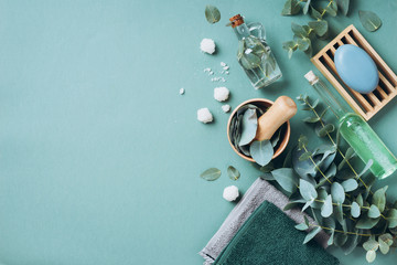 Soap, eucalyptus, towels, massage brush, salt, aroma oil and other spa objects on green background....