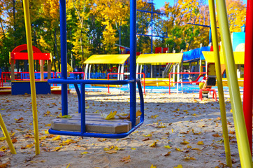Empty playground with carousels and swings on a warm sunny autumn day